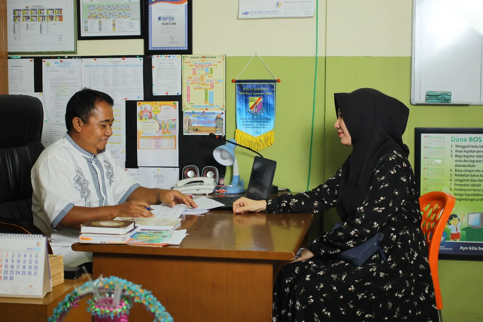 A parent meeting with a school staff member in the school office